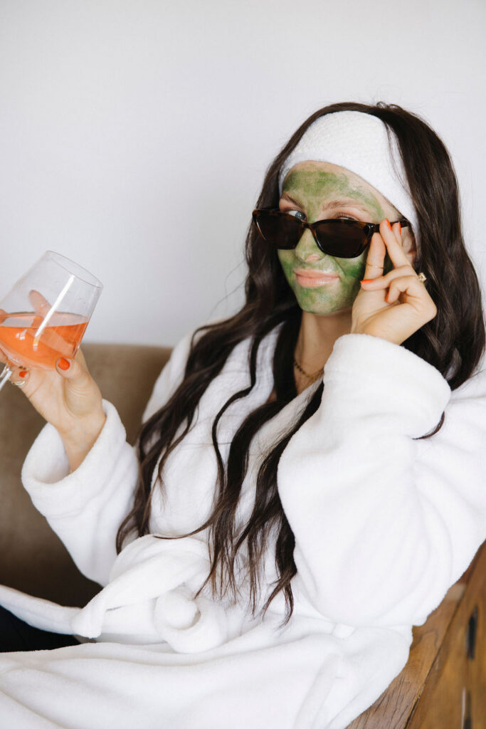 Louisville branding photographer | an esthetician wearing a green face mask with sunglasses and a glass of wine.
