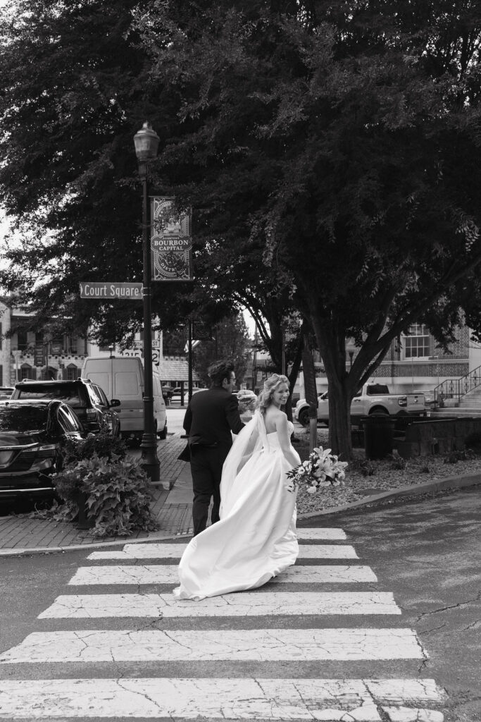 Bride and groom running across the street in downtown Bardstown, Ky.