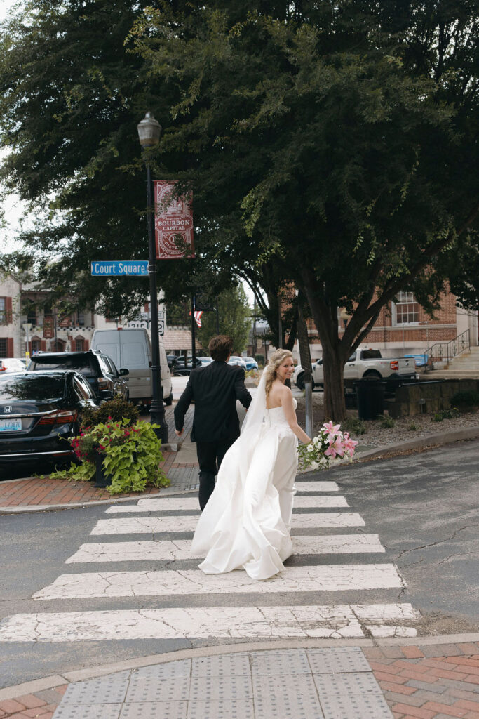 Bride and groom running across the street in downtown Bardstown, Kentucky. 