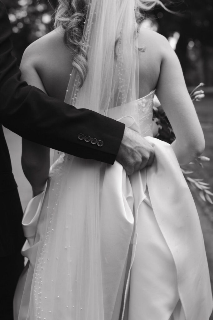 A groom holding his bride's dress in the documentary wedding portraits in Kentucky.