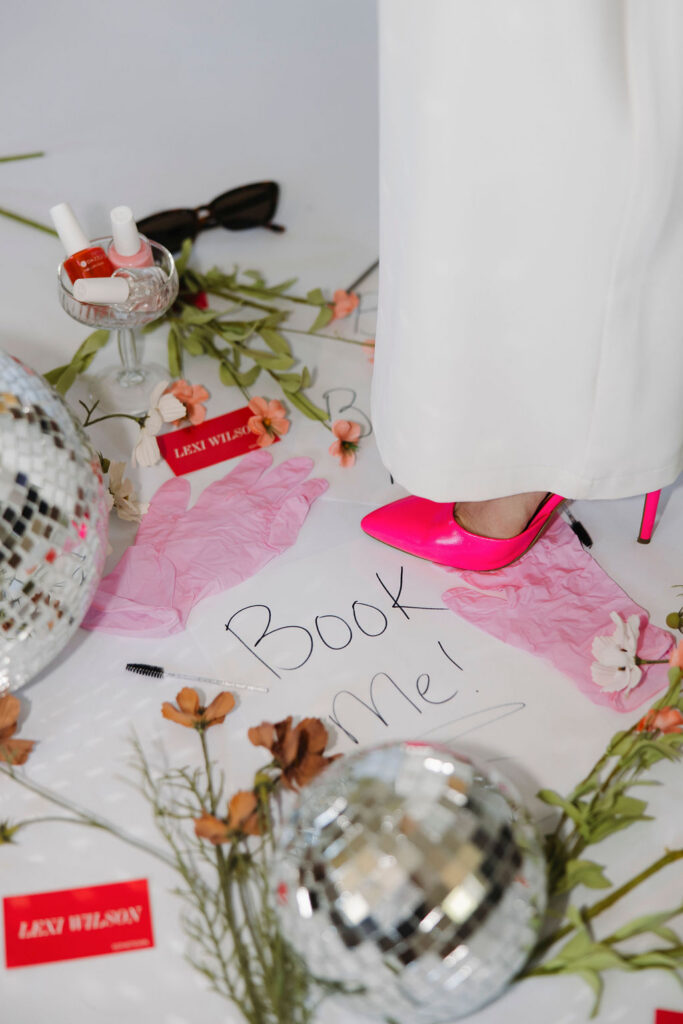 Louisville branding photographer | someone in a hot pink shoe standing on a piece of paper that says book me surrounded by different facial tools.