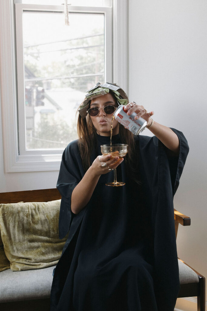 Hairstylist wearing rollers and sunglasses while enjoying a diet coke during a playful retro branding session.