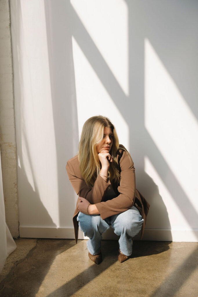 Louisville hairstylist crouching in dramatic natural light during her professional branding session.
