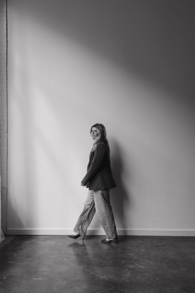 Black and white full body portrait of a hairstylist walking through a Louisville photography studio.
