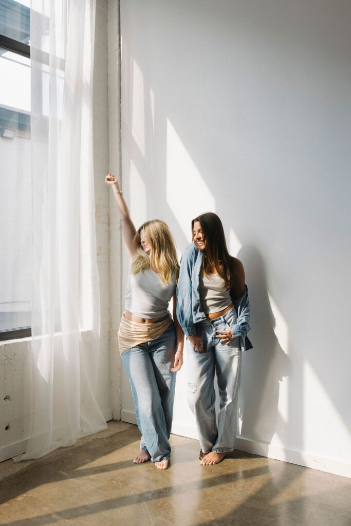 Two hairstylists laughing together in the sunlight during a Louisville branding session.