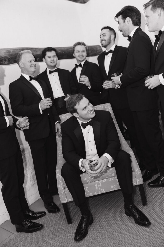 Black-and-white portrait of the groom and groomsmen laughing together.