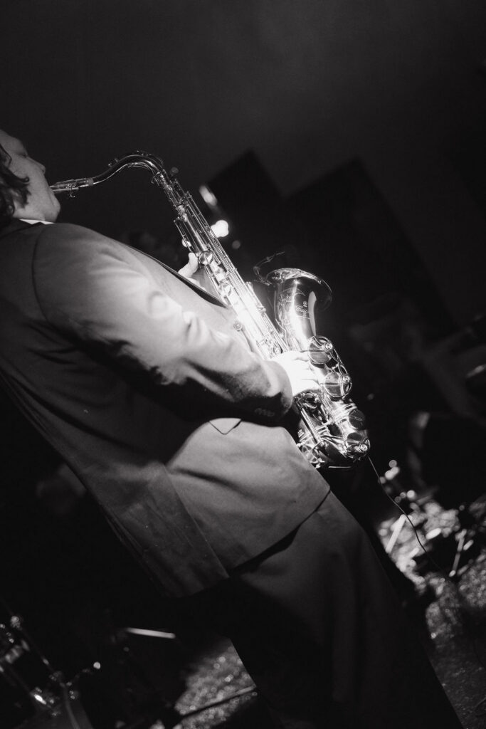Black-and-white photograph of a saxophonist performing at the wedding reception.