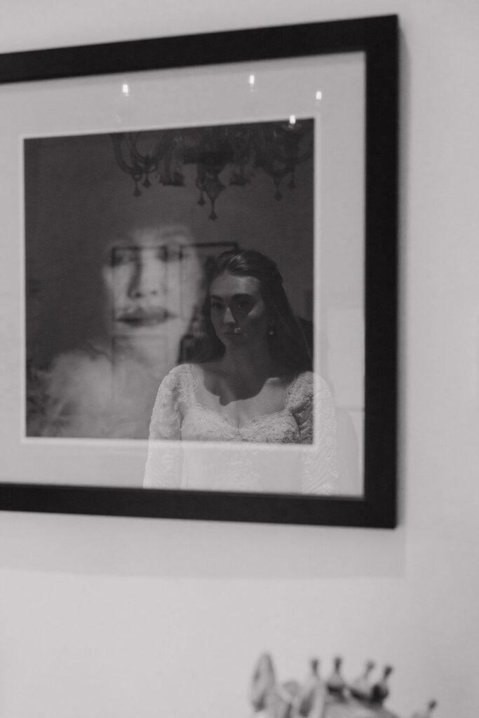 Bride’s reflection appearing in the glass of framed artwork