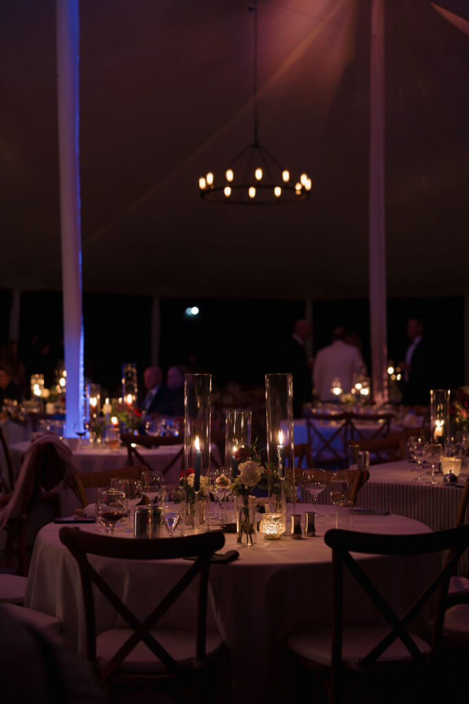 A moody photo of the tented reception space at a black tie wedding at Hermitage Farm with candlelight.