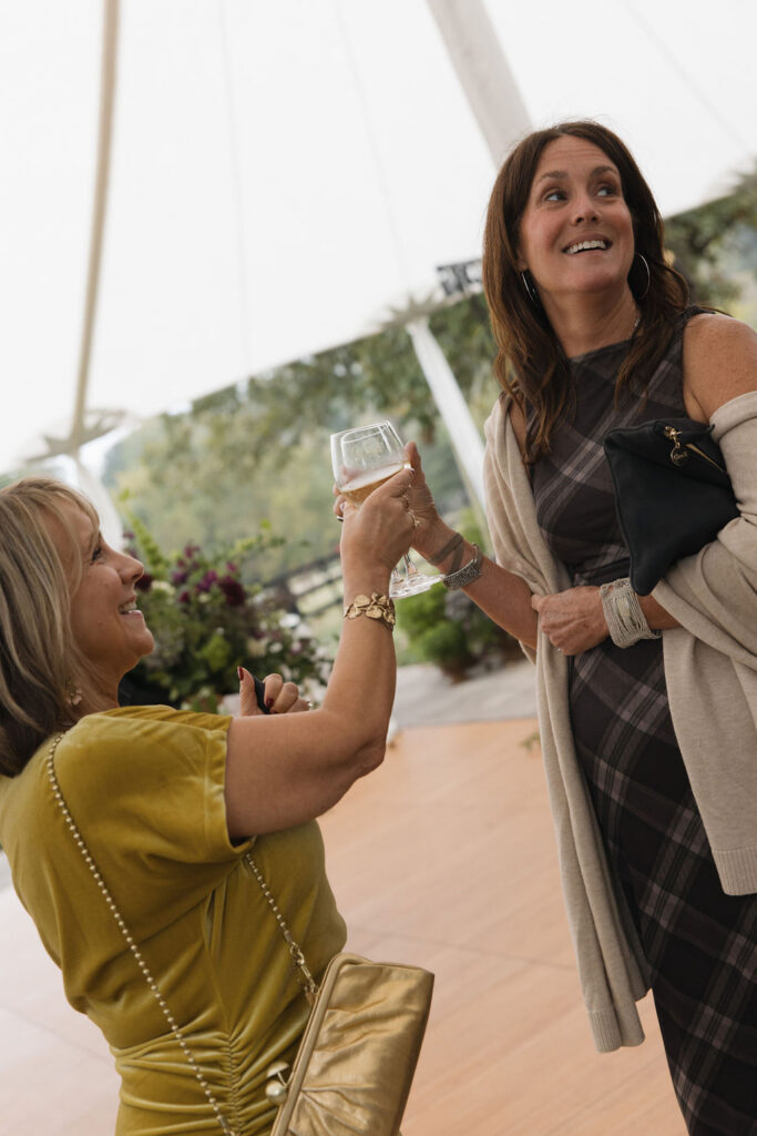 Two guests enjoying glasses of wine at a black tie event at Hermitage Farm.