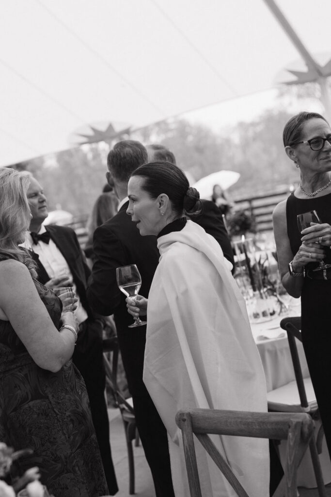 A sophisticated woman at cocktail  hour enjoying conversation with a glass of wine.